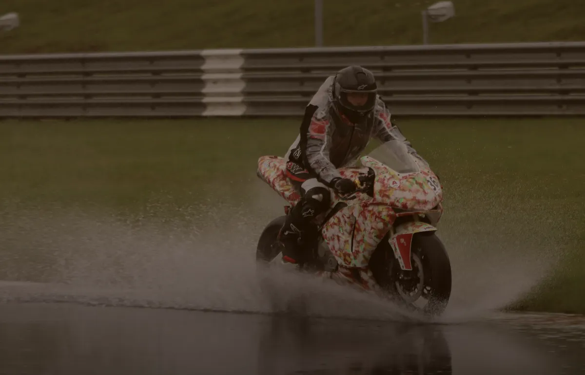Motorkář na sportovním motocyklu na mokré závodní trati během akce MotoDen, RoadPulse